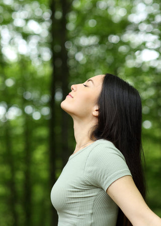 Woman with eyes closed standing in a forest